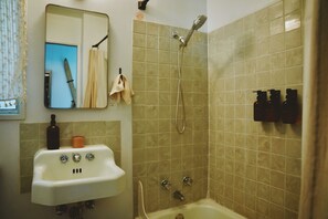 Een badkamer met een wastafel, spiegel, douche en toiletartikelen.