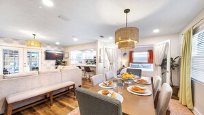 Un comedor moderno con una mesa de madera, sillas y un banco. Dos lámparas colgantes iluminan la mesa.