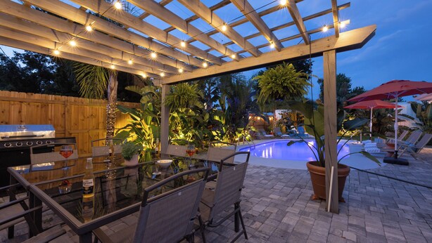 Un patio al aire libre con piscina, pérgola de madera y zona de estar.