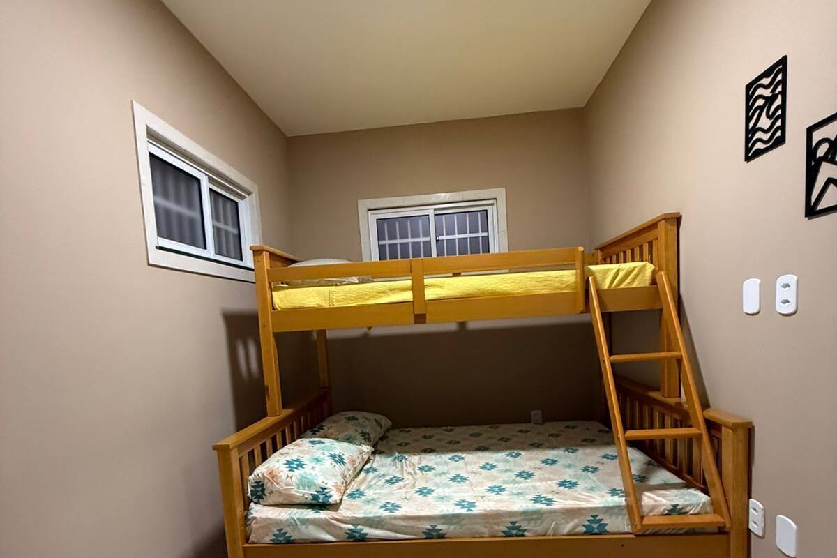 A bunk bed with a ladder, two windows, and a light fixture on the ceiling.