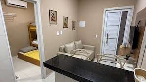 Un espacio habitable compacto con kitchenette, cama, sofá y un pequeño comedor.