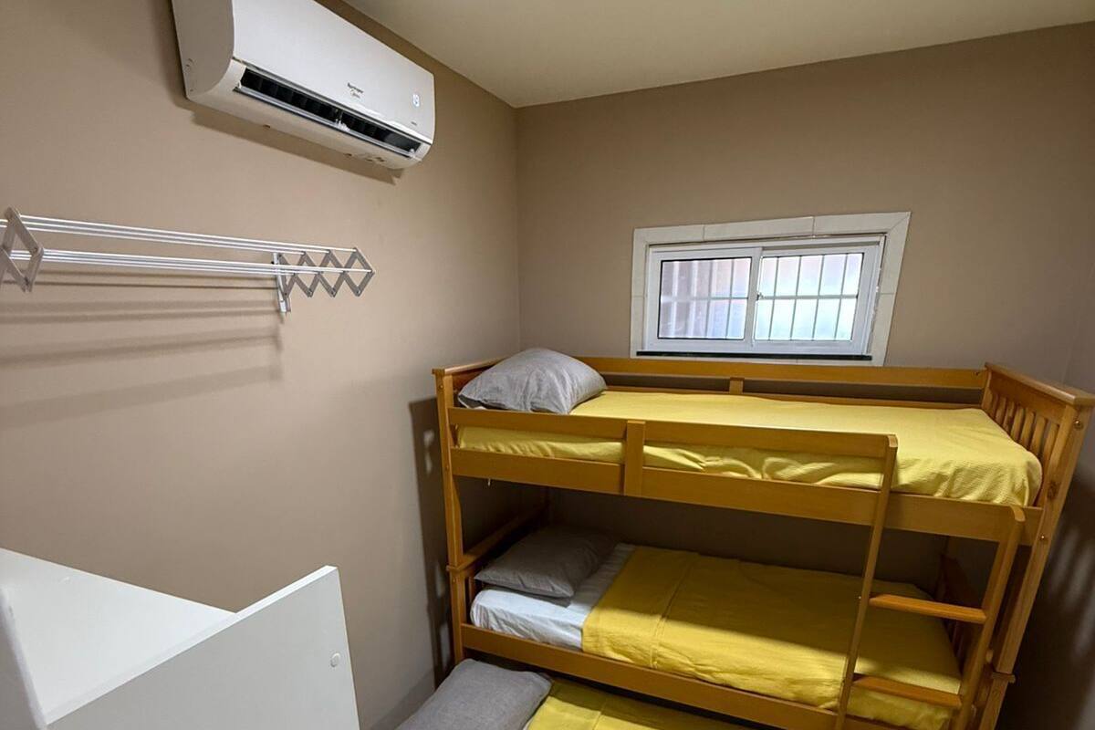 A bunk bed room with a window, an air conditioning unit, and a drying rack.