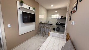 Una cocina moderna con televisor, taburetes de bar y cocina a gas.