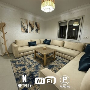 Un salón moderno con un sofá seccional color beige, una mesa de centro de madera y arte abstracto en la pared.