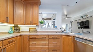 Una cocina con armarios de madera, lavavajillas de acero inoxidable y una encimera con una planta y un tostador.