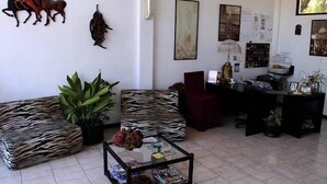 Un salon avec un canapé à motifs zébrés, une table basse en verre et un fauteuil rouge. Des éléments décoratifs sont accrochés aux murs, notamment une sculpture de cheval et un tableau encadré.