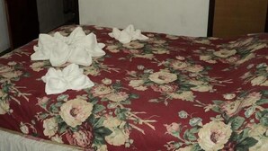 Une pièce avec une couvre-lit à motifs floraux, une petite fenêtre et une porte.