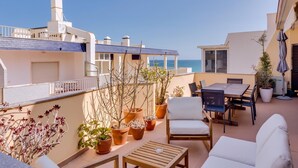 Una terraza en la azotea con una mesa, sillas y plantas en macetas.