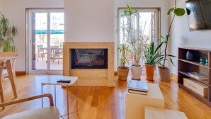 Una sala de estar moderna con chimenea, suelo de madera y plantas en macetas.