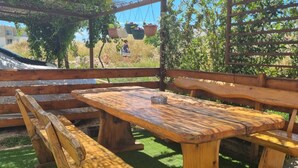 A wooden picnic table with benches, surrounded by a wooden fence and greenery. - Apartments Marija Sukošan (Sukosan)