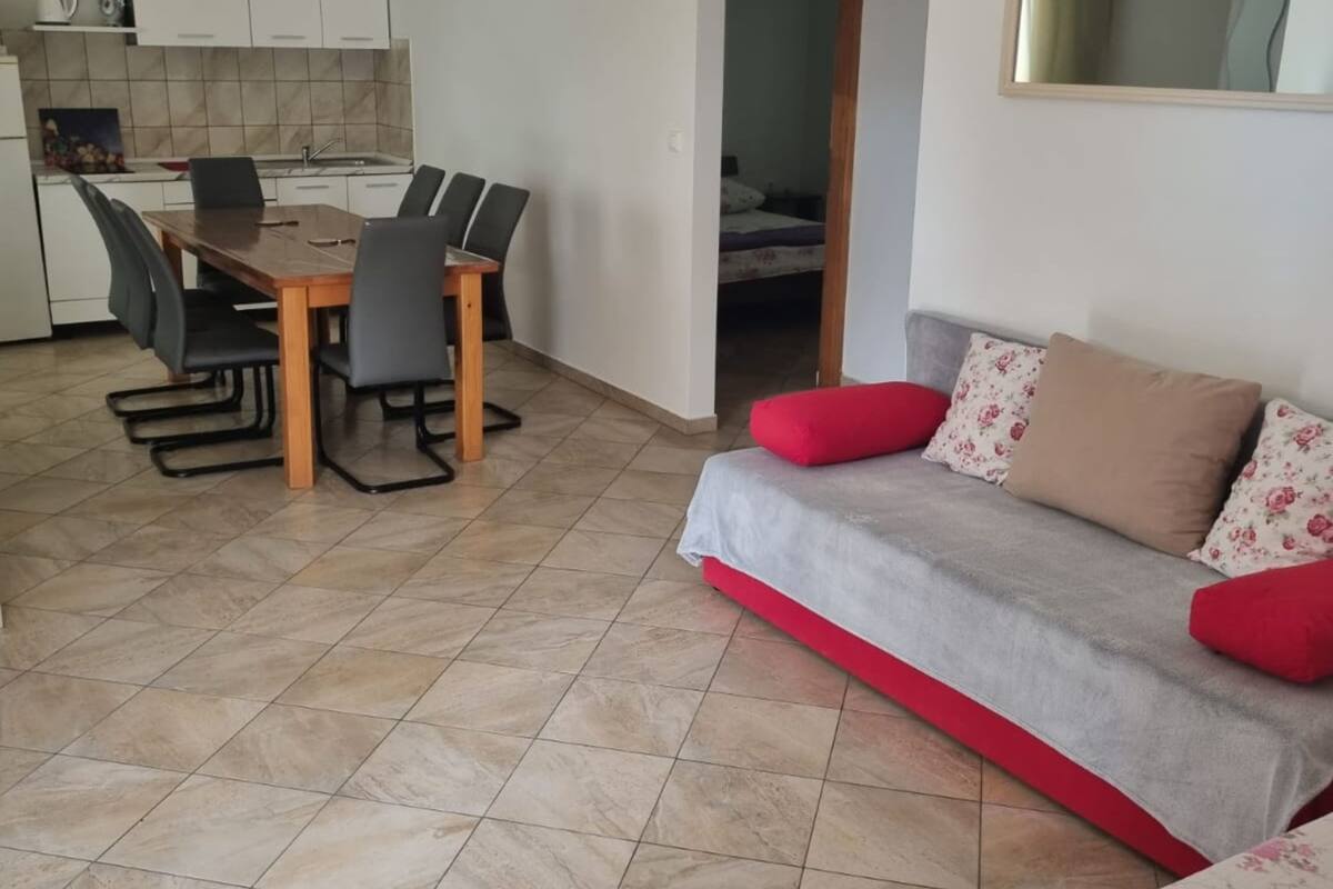 Un espace de vie compact comprenant un coin repas, une kitchenette et un canapé agrémenté de coussins à motifs floraux.