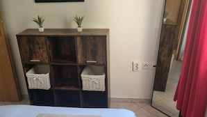 A bedroom with a bed, a wooden wardrobe with baskets, a mirror, and a red curtain. - Apartments Marija Sukošan (Sukosan)
