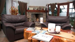 A living room with two leather sofas, a wooden coffee table, and a fireplace. - Apart Raices Patagonicas (Dina Huapi)