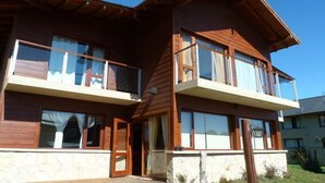 A two-story wooden building with balconies and large windows. - Apart Raices Patagonicas (Dina Huapi)