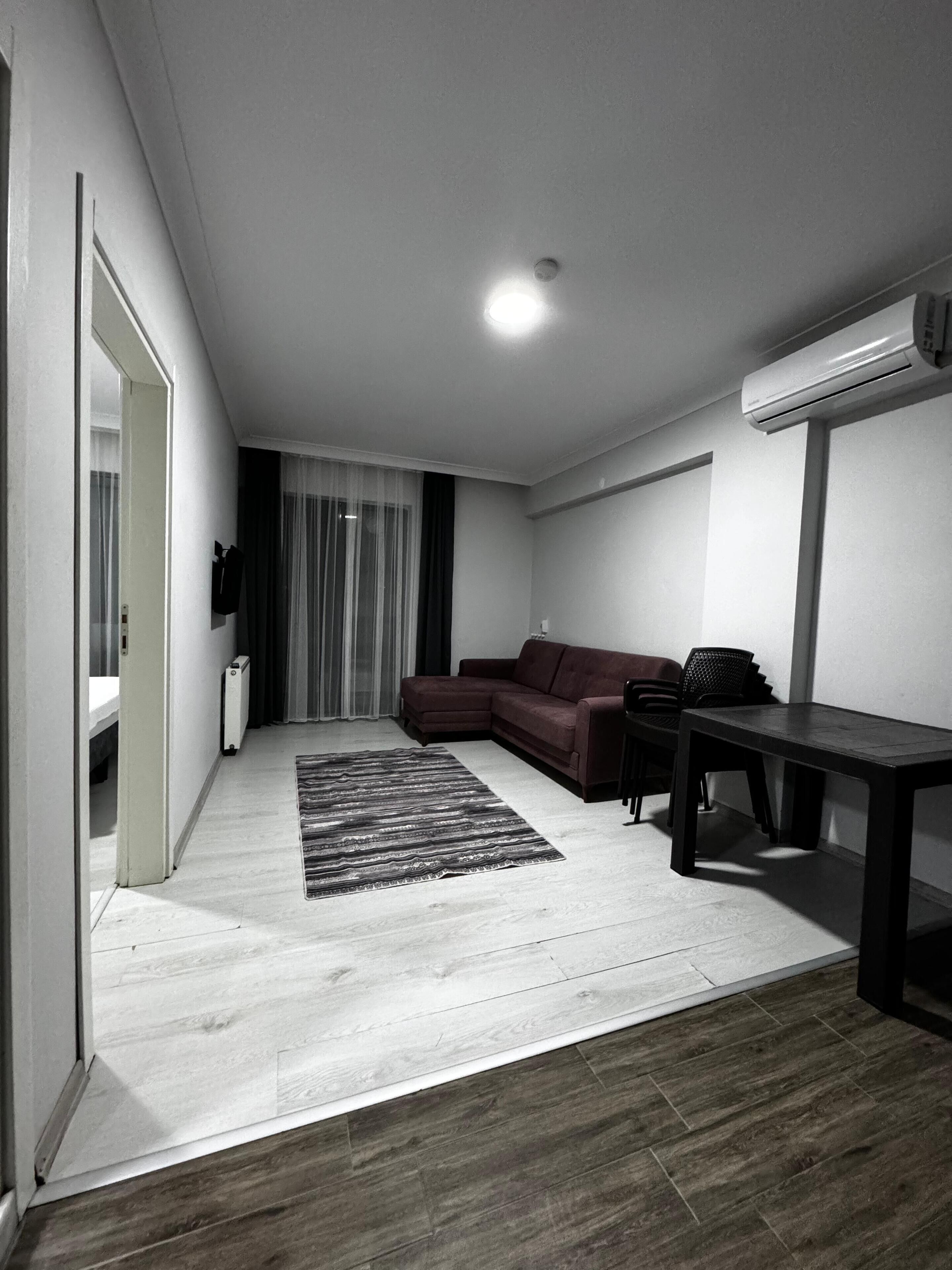 A modern living room with a sectional sofa, a small table, and a dark rug.