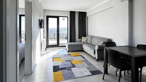 Un salon moderne avec un canapé gris, une table à manger avec des chaises et un tapis à motifs.