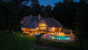 Une maison à deux étages avec une piscine, un espace extérieur aménagé pour se détendre et une terrasse bien éclairée.