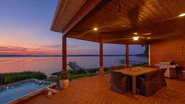 Un espace extérieur abrité doté d’une terrasse en bois, d’un jacuzzi, d’une table à manger avec des chaises et d’un barbecue.