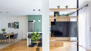 A modern kitchen with a large TV, wooden cabinets, and a dining area with a table and chairs. - Mystique 2-Bedroom Apartment in Athens (Athens)