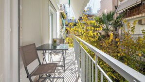 A balcony with a table and chair, surrounded by yellow foliage and a white railing. - Mystique 2-Bedroom Apartment in Athens (Athens)