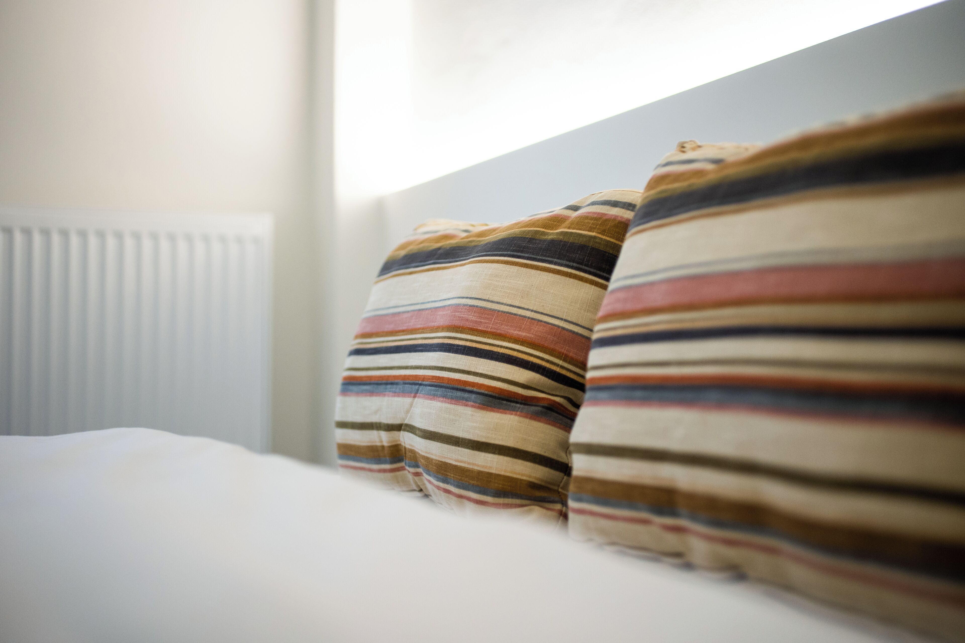 A bed with striped pillows and a white headboard.
