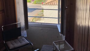A room with a view of the beach, a chair, a table, and a small table.