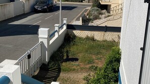 A coastal road with a car parked on the side, a stop sign, and a pedestrian crossing.
