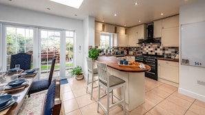 A modern kitchen with a central island, a dining area with a view, and a large window. - Spacious Five Bed Home in the Heart of Cambridge (Cambridge)