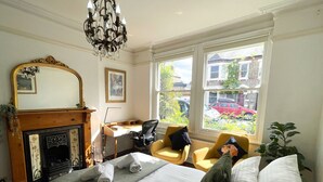 A hotel room with a large bed, a desk, a chair, a fireplace, and a view of the street. - Spacious Five Bed Home in the Heart of Cambridge (Cambridge)