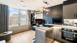 A modern kitchen with a built-in oven, a dining area with a bar stool, and a large window with curtains.