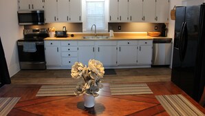 A modern kitchen with white cabinets, stainless steel appliances, and a central island with a vase of flowers.