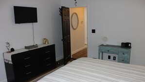 A bedroom with a bed, a dresser, a television, and a door leading to another room. - Charming historic home steps from downtown LaGrange (LaGrange)