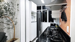 A modern kitchen with white cabinets, a black countertop, a stove, and a refrigerator. - PRIME location: Ipanema, Copacabana and Lagoa — all within reach (Lagoa Rio de Janeiro)