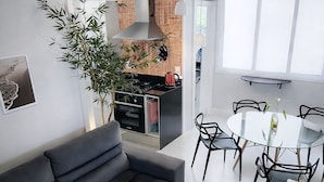 A modern living room with a dark grey sofa, a glass dining table with black chairs, and a kitchen area with red tiles and a chimney. - PRIME location: Ipanema, Copacabana and Lagoa — all within reach (Lagoa Rio de Janeiro)