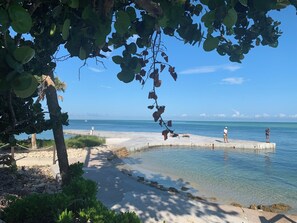 A beach with clear water, a concrete pier, and two people fishing. - Charming condo on Siesta Key close to the Village & the beach (Sarasota)