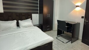 A modern bedroom with a large bed, a wardrobe, a desk, and a chair. - Charming 2-bedroom apartment with AC, WiFi in the Heart of Wuse II, Abuja. (Abuja)