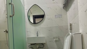 A bathroom with a glass shower enclosure, a white sink with a mirror above it, and a toilet. - Charming 2-bedroom apartment with AC, WiFi in the Heart of Wuse II, Abuja. (Abuja)