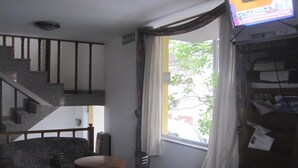 Een kamer met een trap, een bank, een kleine tafel en een televisie.