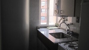 Een keuken met een spoelbak, fornuis en raam.