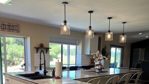 A modern kitchen with a large island, pendant lights, and a dishwasher. - Rest your Kicks off of Route 66 at Rain Valley Inn (Flagstaff)