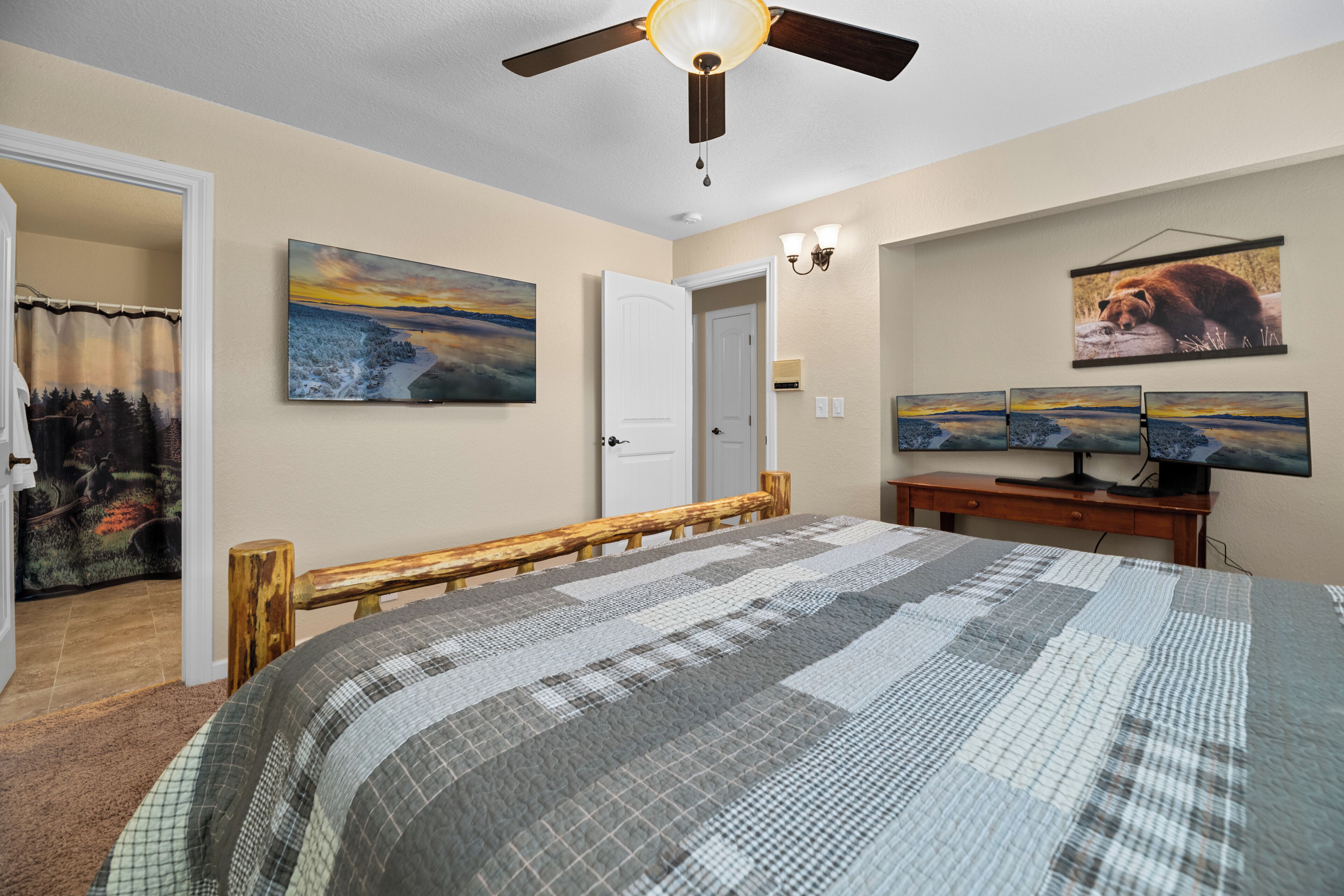 Un dormitorio con cama, ventilador de techo, escritorio con computadora y decoración en la pared.
