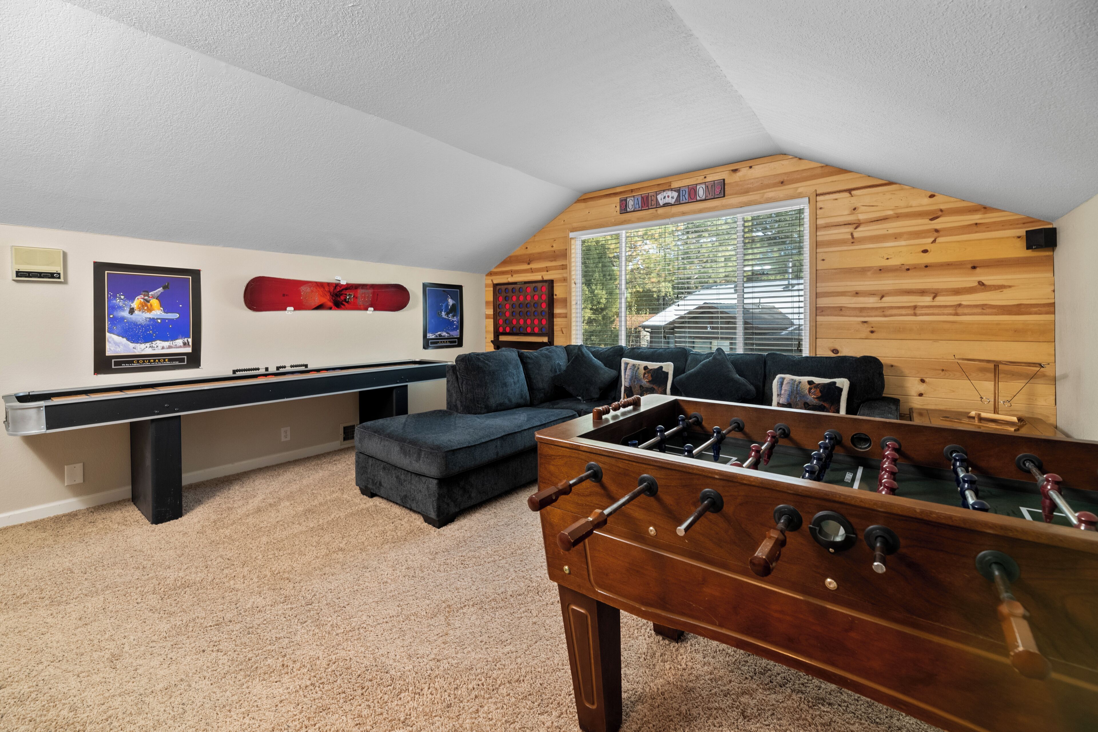 Una habitación acogedora con mesa de fútbol, mesa de billar y un sofá.