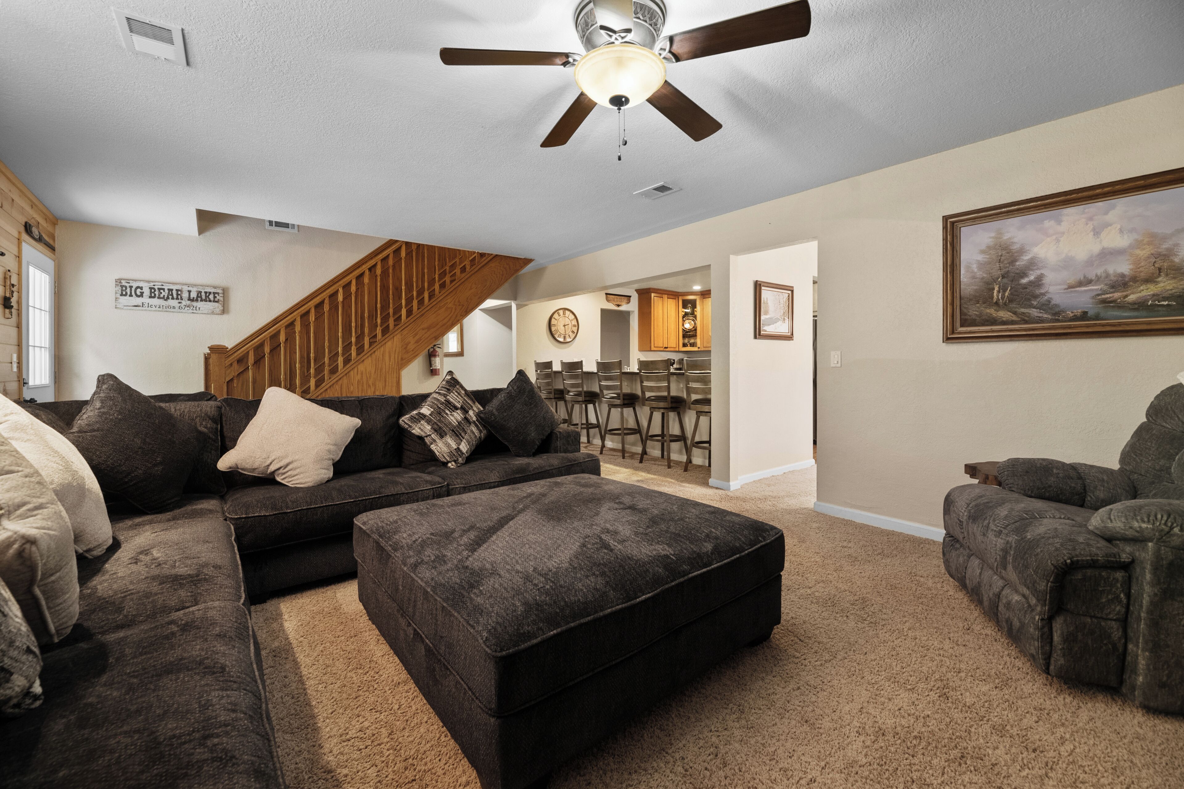 A living room with a sectional sofa, ottoman, and a ceiling fan.