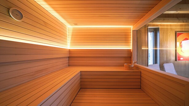 Una sauna de madera con techo inclinado y banco incorporado.