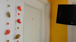 A room with a white door, a television mounted on the wall, and a wall decoration of birds. - La Casa del Girasol Residencia Universitaria (Buenos Aires)