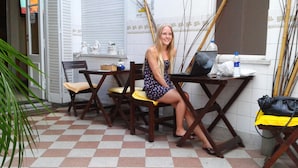 A person seated at a wooden table with a laptop, surrounded by chairs and a small table with items on it. - La Casa del Girasol Residencia Universitaria (Buenos Aires)