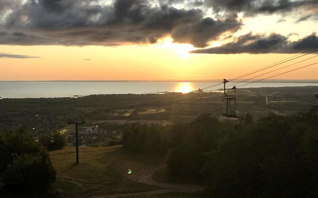 Un capvespre sobre un paisatge costaner amb línies elèctriques i una carretera que condueix cap a un cos d'aigua.