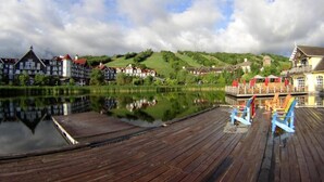 A wooden dock with a calm lake, traditional European-style buildings, and a clear sky. - Slopeside Studio Wifi Towels Ski in Out (Blue Mountain)