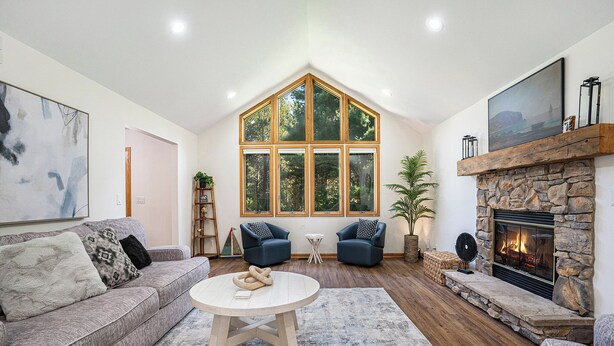 Una sala de estar con un ventanal grande, chimenea, sofá y una mesa de centro.