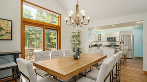 Una cocina moderna con armarios blancos, electrodomésticos de acero inoxidable y una mesa de comedor de madera con sillas.